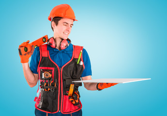Handsome young handyman with a tool belt looking on a plate in hand. House renovation service. Building concept.