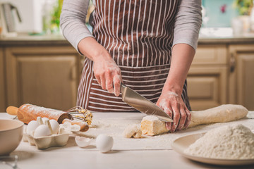 Close-up view of two woman's hands cut knife dough