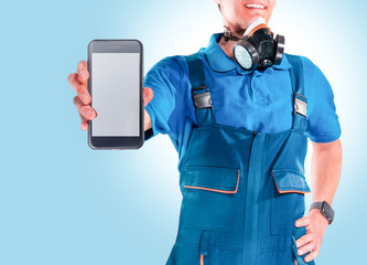 Building painter in protective mask and glasses shows a smartphone on a blu background. Painting concept.