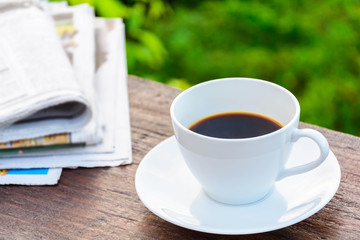 coffee cup clock and news paper on old wooden table
