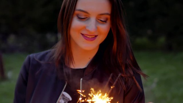 4k Smiling brunette woman holding sparkler or bengal light