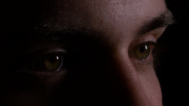 Close up macro of young man eyes looking and searching in the dark