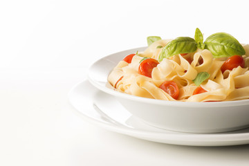 dish with tagliatelle and tomatoes on the white background
