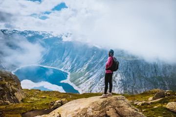 Young woman with backpack standing on fjord coast