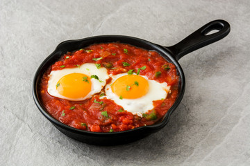 Mexican breakfast: Huevos rancheros in iron frying pan on gray stone
