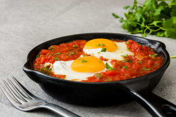 Mexican breakfast: Huevos rancheros in iron frying pan on gray stone
