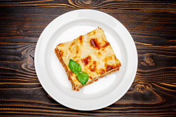 Portion of tasty lasagna on wooden backgound