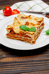 Portion of tasty lasagna on wooden backgound