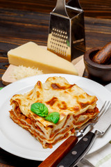 Portion of tasty lasagna on wooden backgound