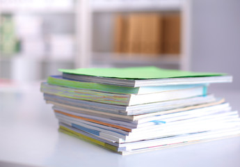 A stack of documentation is on the desktop in the office