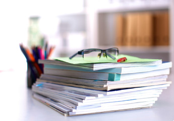 A stack of documentation is on the desktop in the office