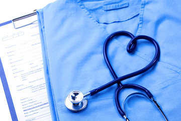 Medical stethoscope twisted in heart shape lying on patient medical history list and blue doctor uniform closeup