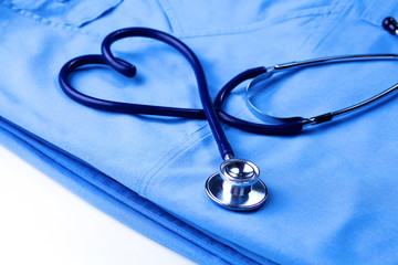 Medical stethoscope twisted in heart shape lying on patient medical history list and blue doctor uniform closeup