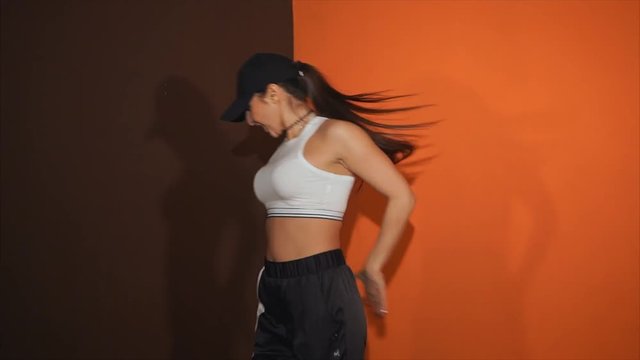 The adult girl shows movements with a body under active music. The dancer trains hip hop - the most fashionable and popular trend of youth culture