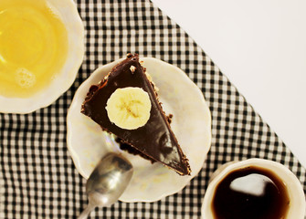 Chocolate cake with milk chocolate on a porcelain saucer near a cup of coffee and honey. Isolated white background. Objects on a background of a black and white background