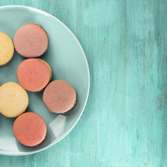 Photo of macarons on teal blue plate with copyspace