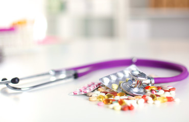 Close up of pills spread over the table with stethoscope and heart lying beside