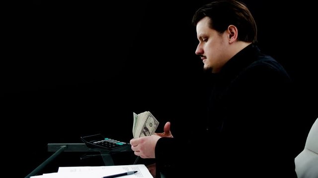A young businessman is putting the money in his pocket on a jacket.