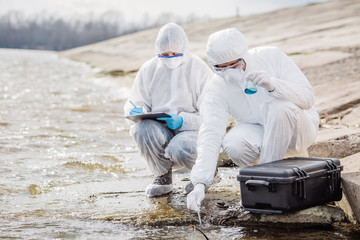 Scientists or biologists wearing protective uniforms working together on water analysis. .