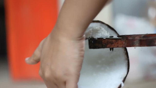Hand of woman using a vintage and old coconut grater for squeeze coconut milk contryside lifestyle