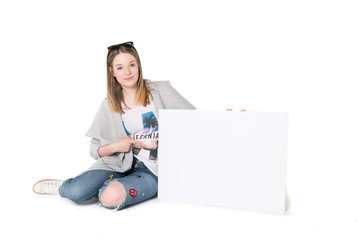 Young beautiful girl in casual clothes holding empty advertisement white cardboard, studio shot isolated, pure white background