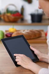 Haman hands  using touch pad in the kitchen. Closeup of woman making online shopping by tablet computer and credit card.  Cooking and shopping concept. 
