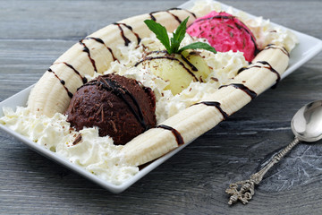 gelato misto con banana e panna montata su sfondo grigio