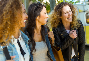 Three beautiful young women walking and talking in the street.