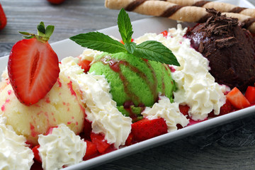 gelato misto fragole cioccolato e menta con panna montata su sfondo grigio
