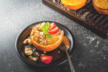 Ideas for a healthy dietary vegan breakfast. Paleo diet. Grilled oranges grapefruits with brown cane sugar, granola, honey, strawberry slices, cashew nuts and mint. On a black stone table. Copy space