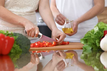Fotobehang Closeup of two women are cooking in a kitchen. Friends having fun while preparing fresh salad © rogerphoto
