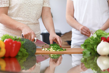 Closeup of two women are cooking in a kitchen. Friends having fun while preparing fresh salad
