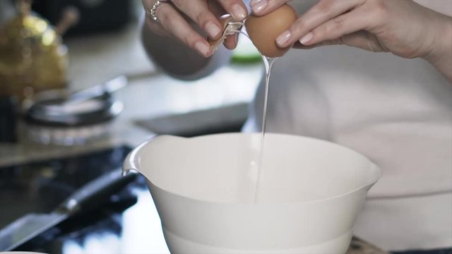 Close up of woman s hands breaking two eggs into a mixer bowl. Locked down real time close up shot