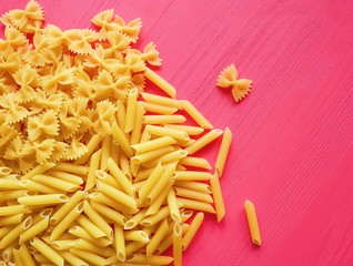 Pasta tubes and bows patterned on the pink bright background