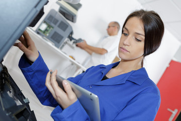 Woman working on electrical appliance, looking at tablet