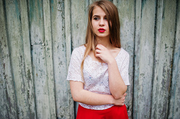 Portrait of beautiful girl with red lips against wooden background, wear on red dress and white blouse.