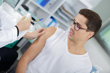 Nervous man having injection in arm