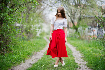 Obraz na płótnie Canvas Portrait of beautiful girl with red lips at spring blossom garden, wear on red dress and white blouse.