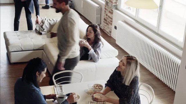 multiethnic friends people having breakfast and getting ready for work indoor in modern industrial house. Businessman and bike use. 4k handheld top view overhead video shot