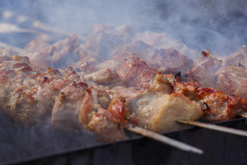 Cooking. Pork meat roasted on a spit. Meat is watered with water, creating splashes and steam. Closeup. When the aperture is wide open, selective focus.