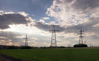 Sun rays above electrical distribution powerlines. Rays of the setting sun after the rain. High voltage transmission powerline.