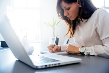 Woman in a white suit writing in her clipboard.