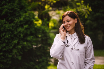 Portrait of young smiling confident female doctor talking on phone