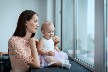 Little girl and her young mother looking out the window