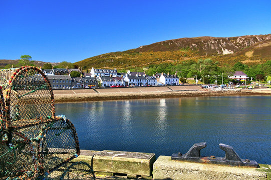 Quay with fish traps and bollard in the foreground and waterfront houses in the background