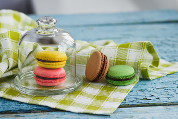 Green, pink and yellow french macarons under the glass on the wooden boards