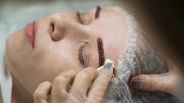 Cosmetology. A girl at a reception in a beauty salon. Eyebrow correction.