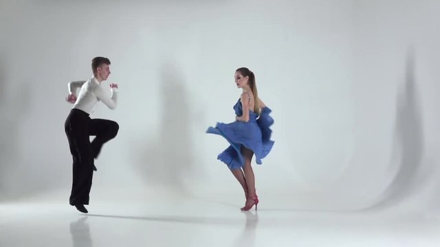 Couple is dancing rumba on white background, shadow. Slow motion