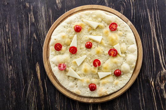 Focaccia with cheese and cherry tomatoes over wooden background