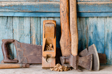 Axes, planer shavings and saw the old blue wooden background.